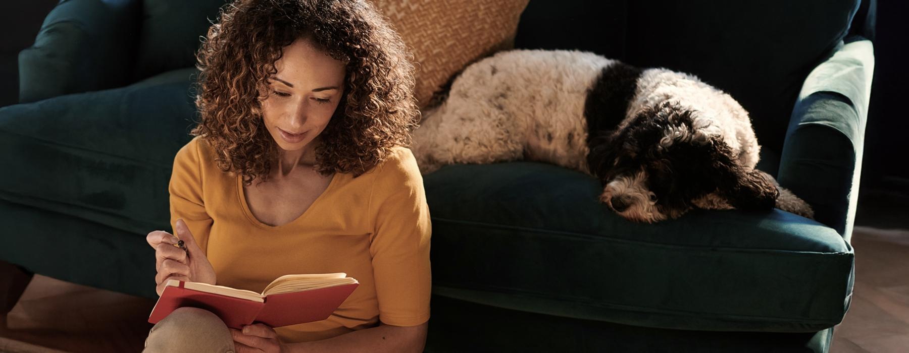 a woman reading a book to a dog